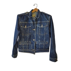 May include: A dark blue denim jacket with a button closure and multiple pockets. The jacket has a classic style and is made of a durable material.