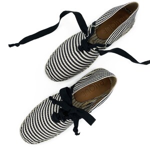 May include: Pair of black and white striped espadrille shoes with black laces. The shoes have the word "RAJOU&Eacute;" written on the insole.