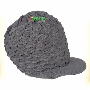 May include: A dark gray knit cap featuring a textured honeycomb pattern across the main body and a solid brim. The hat displays the text ZIONGATES CULCHA SHOP in small, multicolored letters near the top crown area of the knitted fabric.