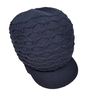 May include: A dark blue knitted beanie with a visor. The beanie has a cable knit pattern.