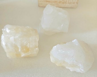 Pode incluir: Três rochas de cristal brancas e translúcidas sobre uma superfície branca texturizada.