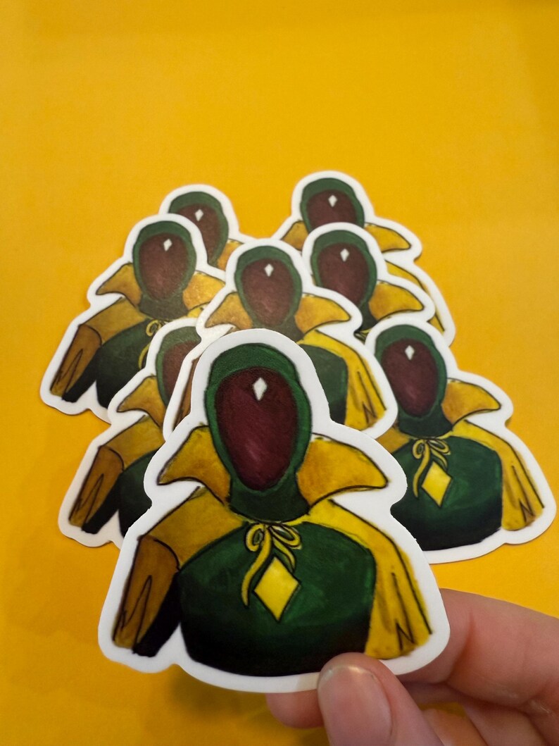 Pu&ograve; includere: Un set di otto adesivi con un personaggio verde e giallo con un diamante sul petto. Il personaggio ha un viso rosso con cappuccio e un mantello giallo.