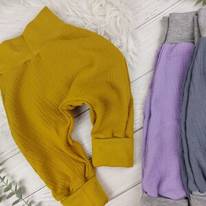 Pu&ograve; includere: Tre paia di pantaloni morbidi in tessuto a nido d'ape per neonati o bambini piccoli. I pantaloni sono di colore giallo senape, lavanda e grigio.