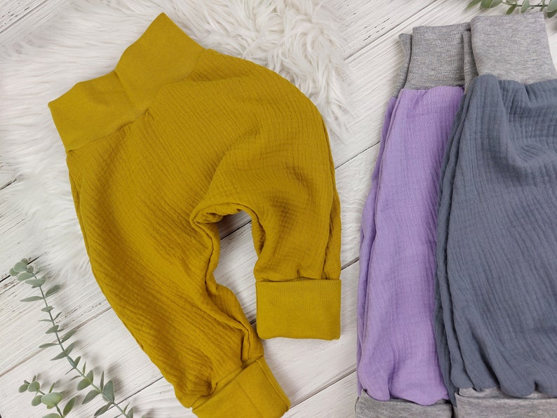 Pu&ograve; includere: Tre paia di pantaloni morbidi in tessuto a nido d'ape per neonati o bambini piccoli. I pantaloni sono di colore giallo senape, lavanda e grigio.