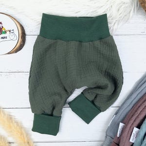Pu&ograve; includere: Pantaloni per neonati di colore verde, in tessuto strutturato con elastico in vita. I pantaloni hanno le gambe con risvolto.