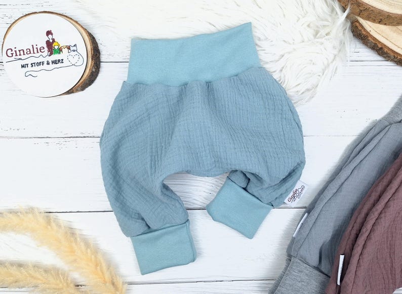 Pu&ograve; includere: Pantaloni per neonati di colore azzurro chiaro con vita elastica e gambe con polsini. I pantaloni sono realizzati in un tessuto morbido e testurizzato.