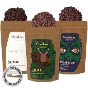 Può includere: Tre sacchetti di carta marrone con chicchi di caffè in cima. Ogni sacchetto ha un'etichetta con il nome "Goodbean" e una miscela di caffè diversa: Espresso, Santos e Offenbarung. Le etichette presentano illustrazioni e testo che descrivono il caffè.