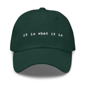 May include: A dark green baseball cap with the text "it is what it is" embroidered in white on the front.