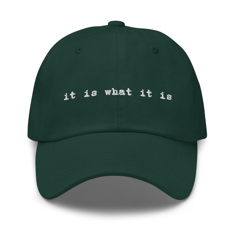 May include: A dark green baseball cap with the text "it is what it is" embroidered in white on the front.