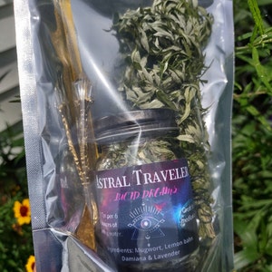 Puede incluir: Una bolsa de pl&aacute;stico transparente que contiene un frasco de vidrio lleno de hierbas secas y un palo de madera. El frasco tiene una etiqueta negra con el texto "Astral Traveler Lucid Dreams" y una lista de ingredientes: Ajenjo, Melisa, Damiana y Lavanda. La etiqueta tambi&eacute;n incluye el texto "1 cucharadita por 170 ml de agua."