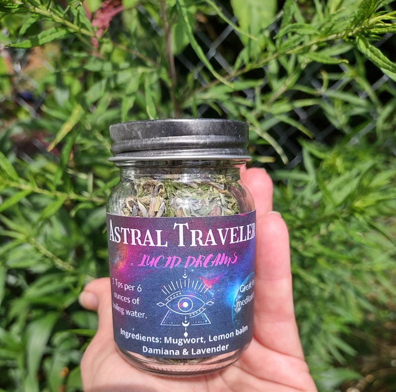 Puede incluir: Un frasco de vidrio con tapa negra lleno de hierbas secas etiquetado como "Astral Traveler Lucid Dreams". La etiqueta tambi&eacute;n incluye el texto "1 cucharadita por 6 onzas de agua hirviendo." e "Ingredientes: Ajenjo, Melisa, Damiana & Lavanda".