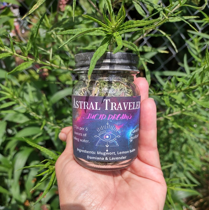 Puede incluir: Un frasco de vidrio con tapa negra lleno de hierbas secas. La etiqueta dice "Astral Traveler Lucid Dreams" y enumera los ingredientes:  Ajenjo, Melisa, Damiana & Lavanda. La etiqueta tambi&eacute;n indica "1 cucharadita por 170 ml de agua hirviendo."