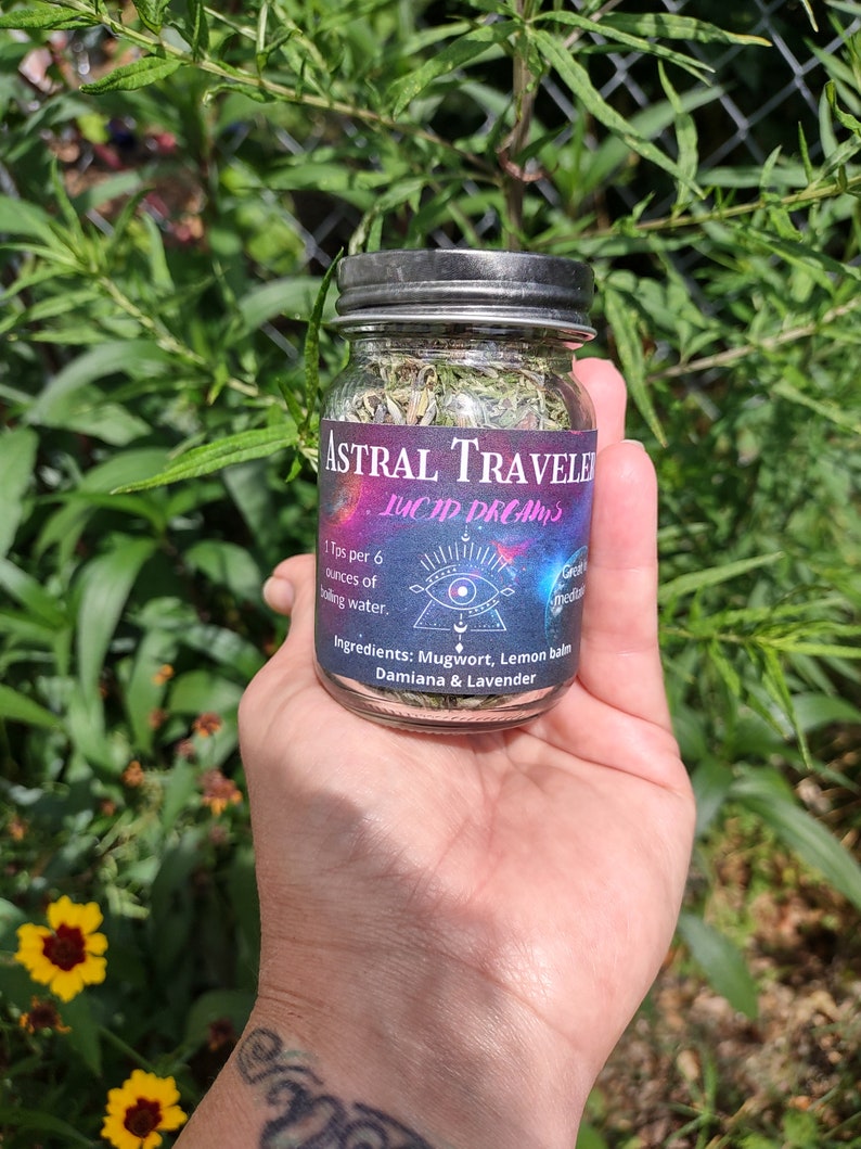 Puede incluir: Un frasco de vidrio lleno de hierbas secas etiquetado como "Astral Traveler Lucid Dreams". La etiqueta tambi&eacute;n incluye el texto "1 cucharadita por 6 onzas de agua hirviendo." e "Ingredientes: Ajenjo, Melisa, Damiana & Lavanda".