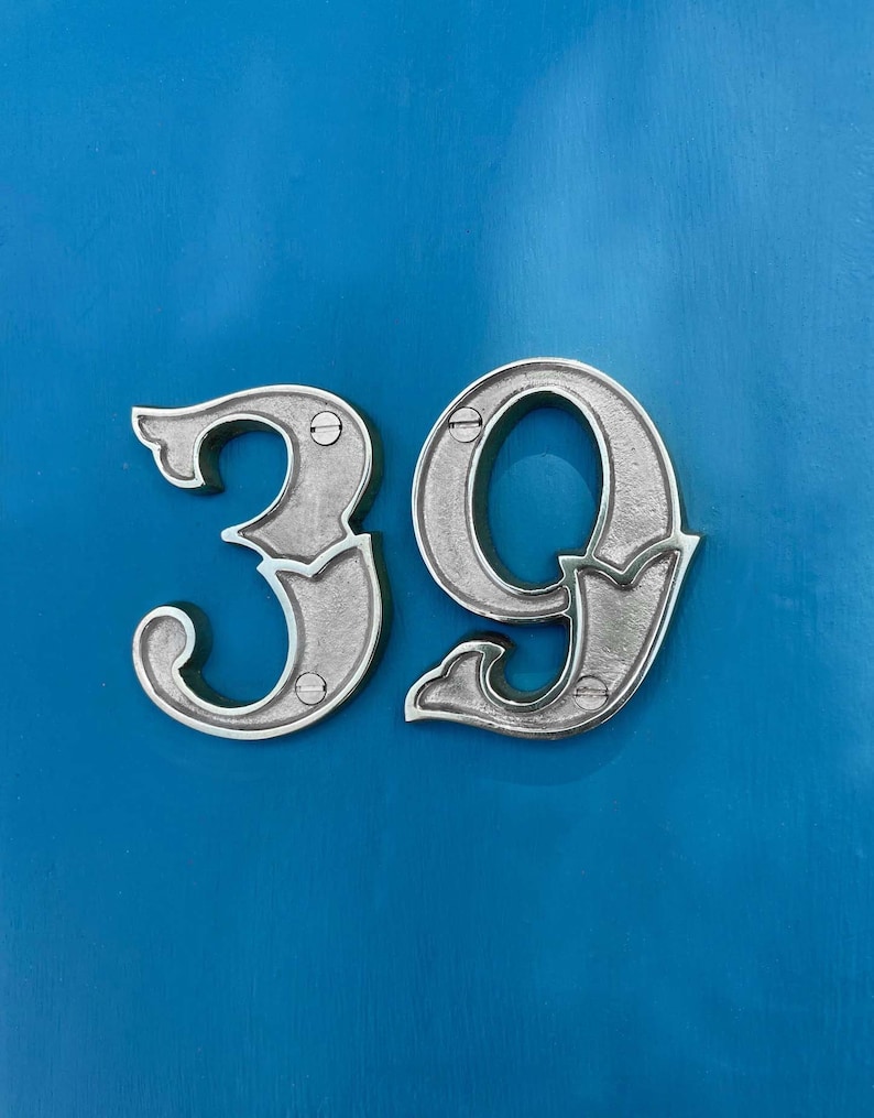 May include: Silver metal house number 39 on a bright blue background.