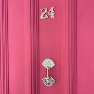 May include: A bright pink door with a gold door knocker and the number 24 in gold lettering.
