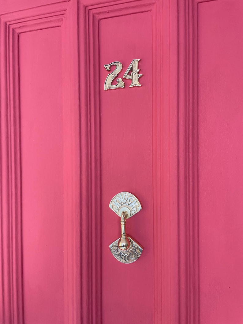 May include: A bright pink door with a gold door knocker and the number 24 in gold lettering.