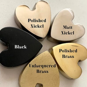May include: Five heart-shaped metal samples in different finishes: polished nickel, matte nickel, black, polished brass, and unlacquered brass.
