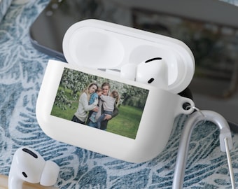 Puede incluir: Funda blanca para Airpods con una foto de una familia de tres personas en un parque. La foto muestra a una mujer, un hombre y un niño pequeño.