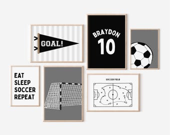 Puede incluir: Una colección de láminas artísticas enmarcadas con temática de fútbol. Las láminas presentan un banderín negro con "GOAL!", una camiseta negra con "BRAYDON 10", un balón de fútbol, una portería de fútbol, un diagrama de campo de fútbol y el texto "EAT SLEEP SOCCER REPEAT".