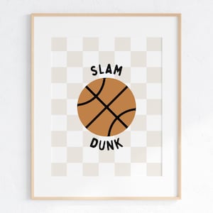 Peut inclure: Une impression encadrée avec un fond à carreaux représentant un ballon de basket brun avec des lignes noires et le texte "SLAM DUNK" en noir.