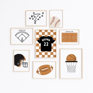Op de afbeelding: Een set van acht ingelijste prints met verschillende sportthema-illustraties. De prints zijn in een minimalistische stijl met zwarte en bruine contouren op een witte achtergrond. De prints omvatten een honkbalveld, een basketbalveld, een voetbal, een basketbalring, een honkbal, een shirt met de naam "BROWN" en het nummer "22", een voetbalhelm en een speldiagram.
