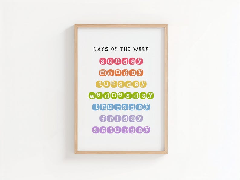 May include: A framed print with the text "DAYS OF THE WEEK" in black. The days of the week are listed in a rainbow of colors: red, orange, yellow, green, blue, purple. The frame is a light brown color.