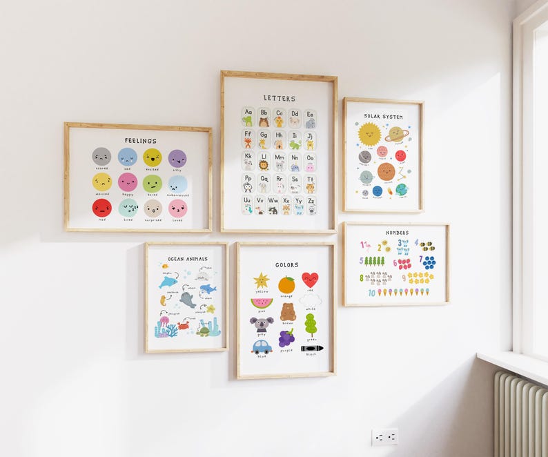 May include: A collection of framed educational posters on a white wall. The posters feature colorful illustrations of feelings, letters, ocean animals, colors, the solar system, and numbers. Each poster has a wooden frame.