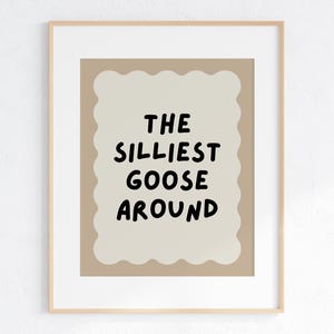 Puede incluir: Una impresi&oacute;n enmarcada beige con un fondo marr&oacute;n y un borde blanco festoneado. El texto dentro del borde dice "The Silliest Goose Around" en negro.