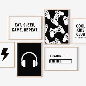 May include: Set of six black and white printable wall art prints with gaming and gamer themes. The prints feature text such as "Eat, Sleep, Game, Repeat", "Cool Kids Club", and "Loading..." along with images of a lightning bolt, headphones, and a video game controller.