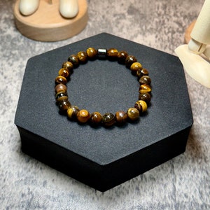 May include: A brown and gold tiger's eye beaded bracelet with a silver magnetic clasp.