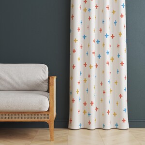 Puede incluir: Una cortina blanca con un patrón repetitivo de signos más coloridos en rojo, amarillo y azul. La cortina está colgada frente a una pared azul oscuro.