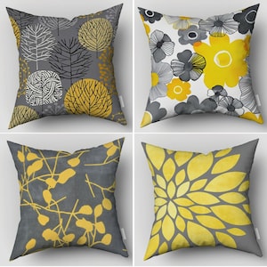 Può includere: Quattro cuscini decorativi con un motivo floreale grigio e giallo. I cuscini sono quadrati e hanno una texture morbida e soffice.