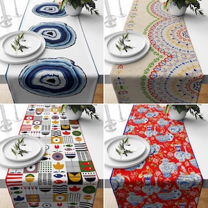 Może przedstawiać: Cztery różne bieżniki stołowe z różnymi wzorami. Pierwszy bieżnik ma geometryczny wzór w kolorze niebieskim i białym. Drugi bieżnik ma beżowe tło z kolorowym wzorem mandali. Trzeci bieżnik ma czerwone tło z kolorowym wzorem kwiatowym. Czwarty bieżnik ma białe tło z kolorowym geometrycznym wzorem.