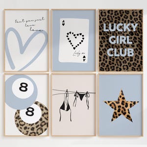 May include: Six framed art prints with a light wood frame. The prints feature various designs, including a blue heart, a playing card with a heart design, the text "LUCKY GIRL CLUB", a pool ball, a bikini, and a leopard print star.
