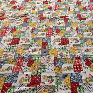 May include: A patchwork quilt in a variety of colours, including red, yellow, blue, green, and white. The squares feature repeating patterns, including floral designs and figures. The quilt is made of fabric.