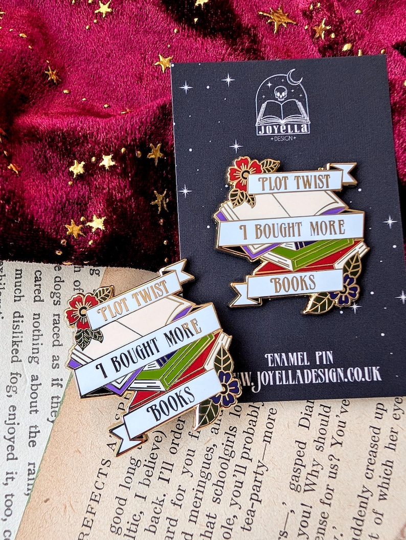 May include: Two gold enamel pins with a book stack design. The top pin reads "Plot Twist I Bought More Books". The bottom pin reads "Plot Twist I Bought More Books".