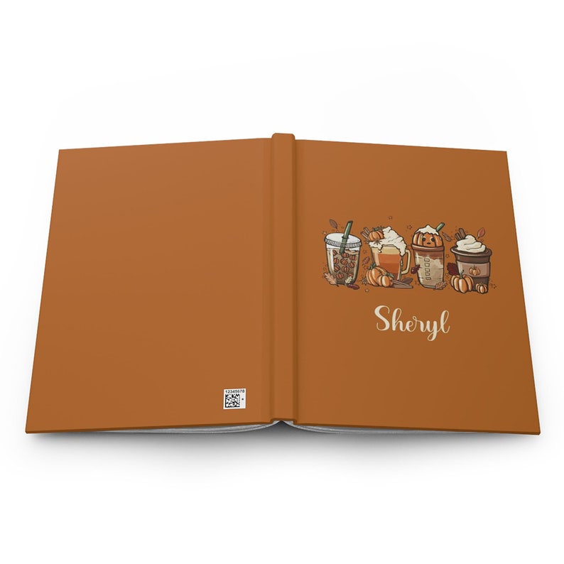 K&ouml;nnte beinhalten: Ein offenes orangefarbenes Buch mit dem personalisierten Namen "Sheryl" auf der rechten Seite. Die linke Seite ist leer. Die rechte Seite zeigt eine farbenfrohe Illustration von vier Herbstgetr&auml;nken mit K&uuml;rbisgew&uuml;rz und Herbstbl&auml;ttern.