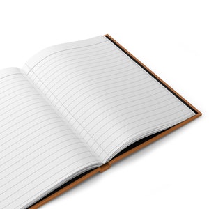 K&ouml;nnte beinhalten: Ein ge&ouml;ffnetes, liniertes Notizbuch mit braunem Lederumschlag. Das Notizbuch liegt flach auf einer wei&szlig;en Oberfl&auml;che.