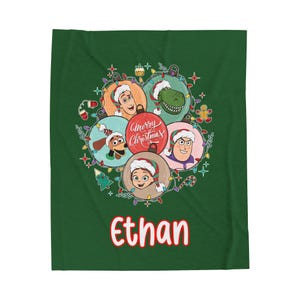 May include: A green blanket featuring a festive design with cartoon characters wearing Santa hats. The design includes the text "Merry Christmas" and the name "Ethan" in red. The blanket is decorated with Christmas lights and ornaments.