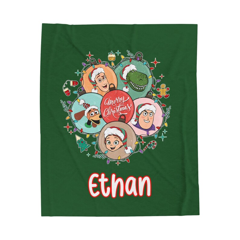 May include: A green blanket featuring a festive design with cartoon characters wearing Santa hats. The design includes the text "Merry Christmas" and the name "Ethan" in red. The blanket is decorated with Christmas lights and ornaments.