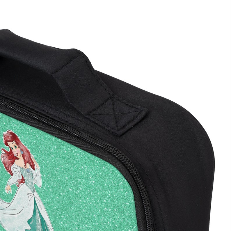 May include: A black zippered lunch bag with a green glitter background and a graphic of Ariel from The Little Mermaid. The bag has a black padded handle.