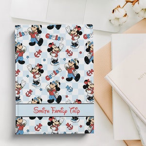 May include: A blue and white checkered notebook with a Mickey Mouse cruise theme. The cover features Mickey Mouse and Minnie Mouse in various poses, with the words "Cruise" and "Smith Family Trip" printed on the cover.