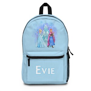 K&ouml;nnte beinhalten: Hellblauer Rucksack mit einer Aquarellillustration von zwei Charakteren aus dem Film Frozen, mit einem Schloss im Hintergrund. Der Name "Evie" ist in Wei&szlig; auf der Vordertasche aufgedruckt. Er hat einen schwarzen Griff und Rei&szlig;verschluss.