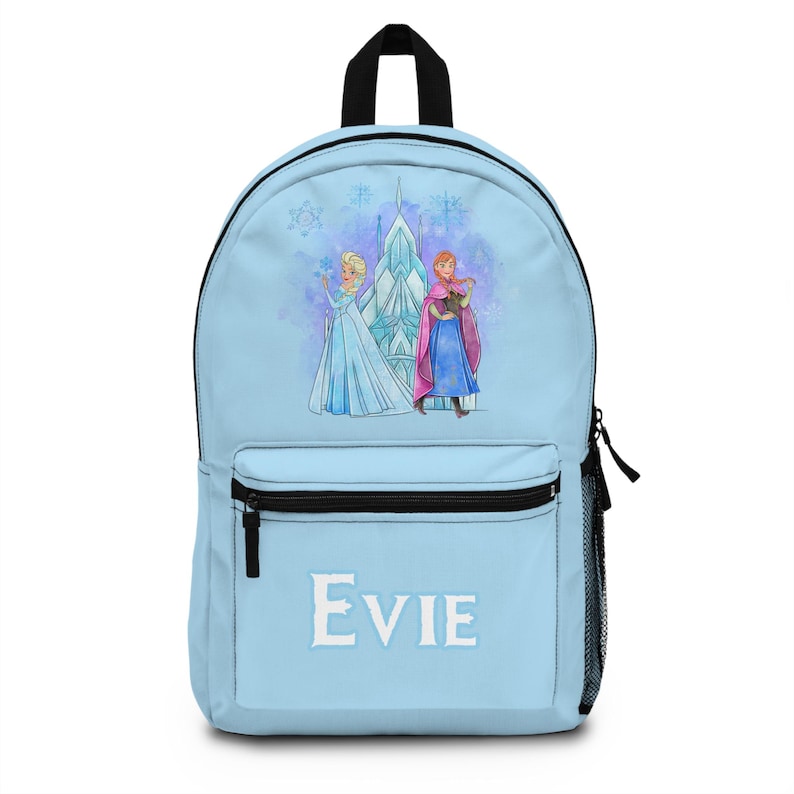 K&ouml;nnte beinhalten: Hellblauer Rucksack mit einer Aquarellillustration von zwei Charakteren aus dem Film Frozen, mit einem Schloss im Hintergrund. Der Name "Evie" ist in Wei&szlig; auf der Vordertasche aufgedruckt. Er hat einen schwarzen Griff und Rei&szlig;verschluss.
