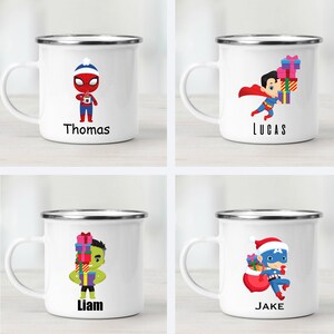 Puede incluir: Cuatro tazas de esmalte blanco con bordes plateados. Cada taza presenta un personaje de superh&eacute;roe diferente sosteniendo regalos. Las tazas est&aacute;n etiquetadas con los nombres "Thomas", "Lucas", "Liam" y "Jake".