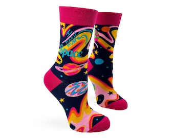 May include: A pair of colorful socks with a space theme. The socks are navy blue with pink, yellow, orange, and blue planets, stars, and swirls. The text on the socks reads "I need more space".