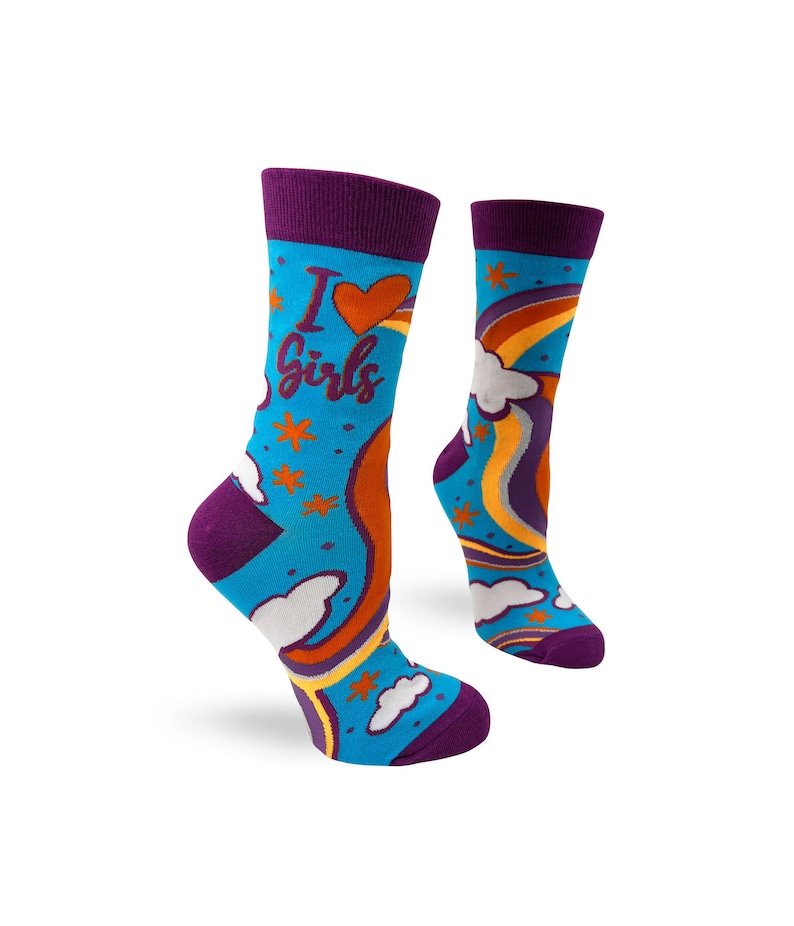 May include: A pair of blue socks with a rainbow, clouds, and stars pattern. The socks have a purple cuff and the left sock has the text "I love girls" in purple.