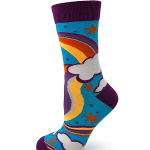 May include: A pair of colorful socks with a rainbow and clouds design. The socks are blue, purple, yellow, orange, and white.