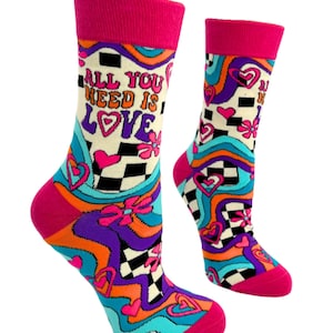 May include: A pair of colorful socks with a checkered pattern and the words "All You Need Is Love" in a retro font. The socks have a pink cuff and feature hearts, flowers, and wavy lines.