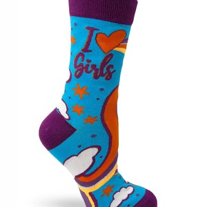 May include: A pair of blue socks with a rainbow, clouds, and stars pattern. The socks have a purple cuff and the text "I love girls" is printed on the front.